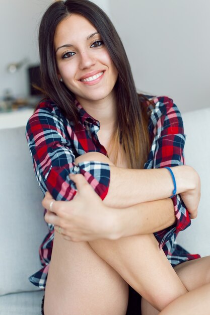 Femme assise sur le canapé et souriante