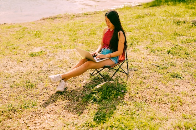 Femme assise sur une chaise à l&#39;extérieur avec un ordinateur portable