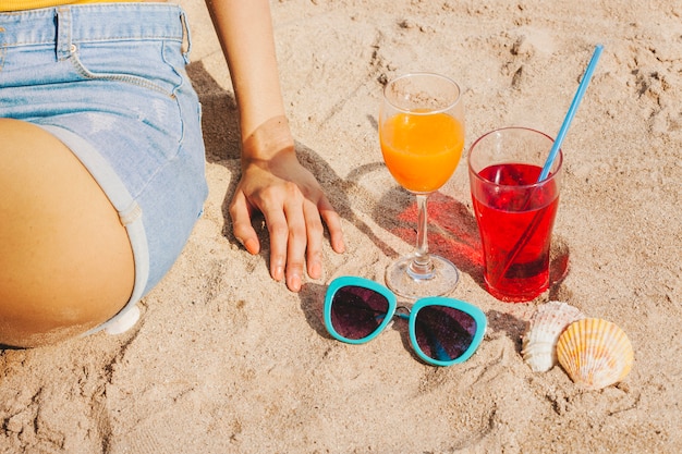 Femme assise à côté de boissons et lunettes de soleil