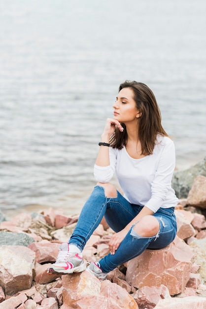 Femme assise à côté de la mer