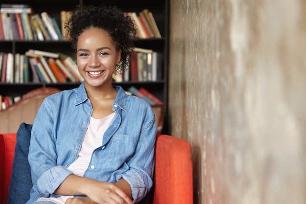 Photo gratuite femme assise dans une bibliothèque sur un canapé