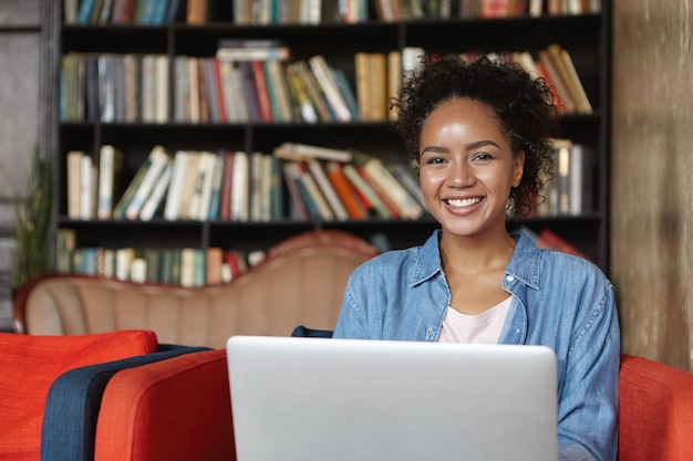 Femme assise dans une bibliothèque avec son ordinateur portable