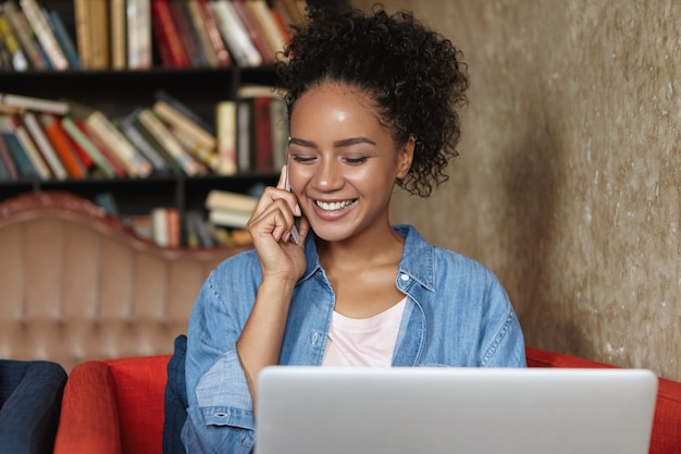 Photo gratuite femme assise dans une bibliothèque avec son ordinateur portable