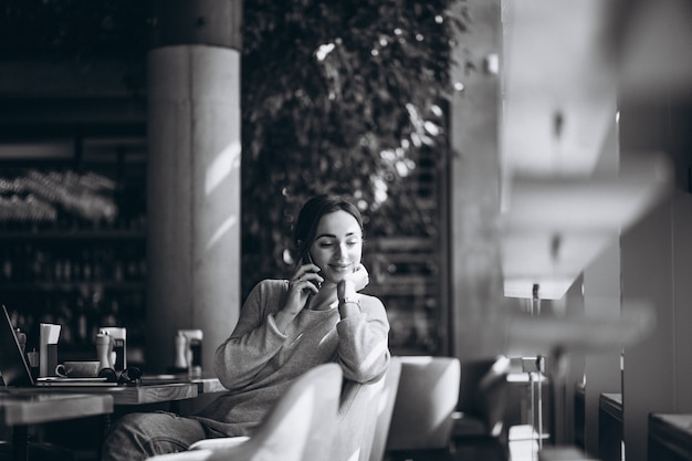 Photo gratuite femme assise dans un café, buvant du café et travaillant sur un ordinateur