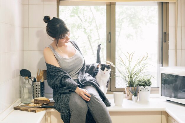 Femme assise dans la cuisine avec son chat