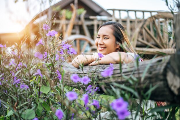 femme assise dans le jardin de fleurs et posant ses mains vers la clôture en bois