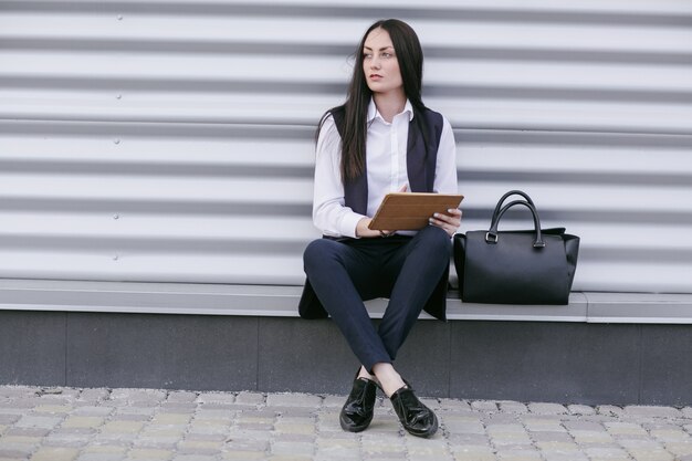 Femme assise dans la rue avec une tablette dans les mains