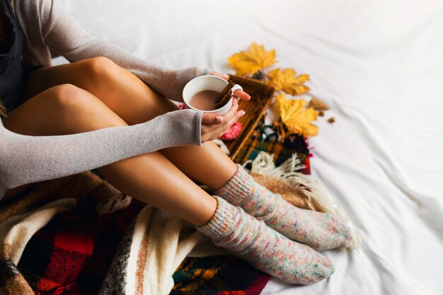 femme assise dans son lit avec des livres et boire du café avec de la cannelle, des biscuits et des beignets glacés.