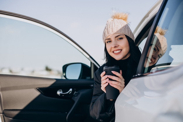 Femme assise dans la voiture et boire du café