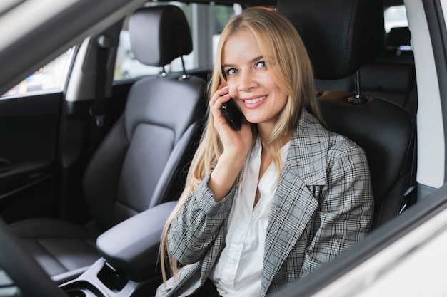 Femme assise dans la voiture tout en parlant au téléphone