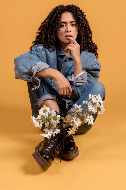 Femme assise avec des fleurs en bottes