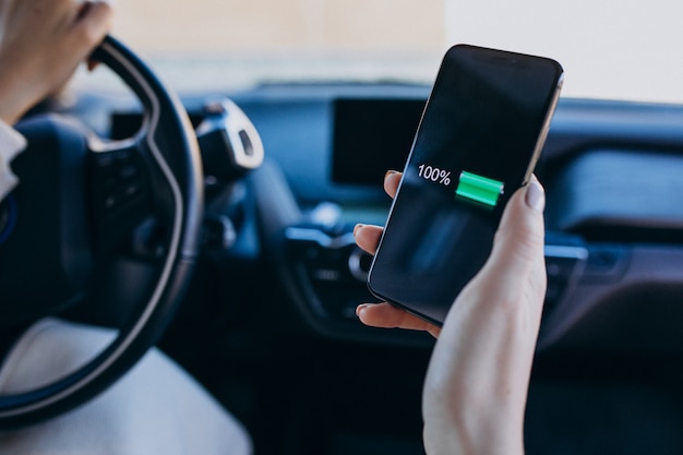 Femme assise à l'intérieur de la voiture électrique pendant le chargement