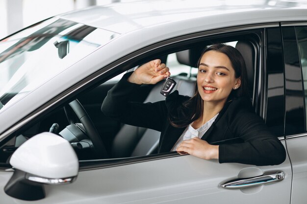 Femme assise à l'intérieur d'une voiture et tenant les clés