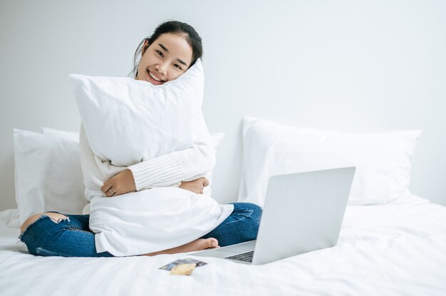 La Femme Assise Sur Le Lit Et étreignant L'ordinateur Portable.