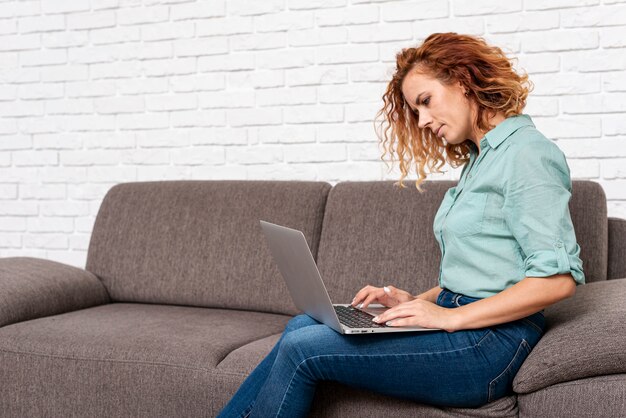 Femme assise lors de la vérification d'un ordinateur portable