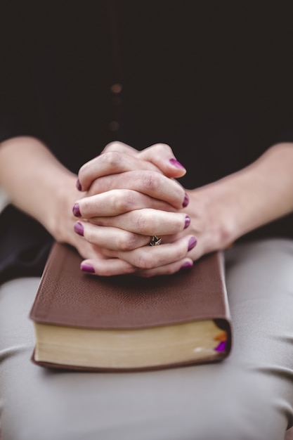 Femme assise avec la main sur un livre sur ses genoux