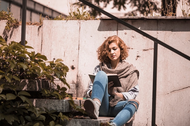 Femme assise sur les marches et livre de lecture