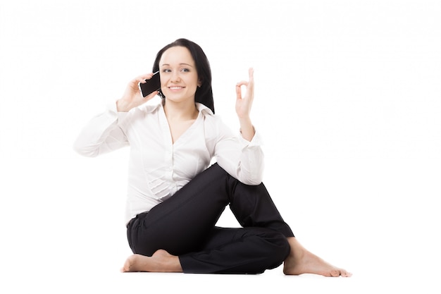 Femme assise sur le plancher de parler sur son téléphone