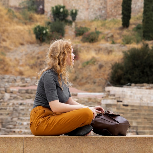 Femme assise près de sac à dos