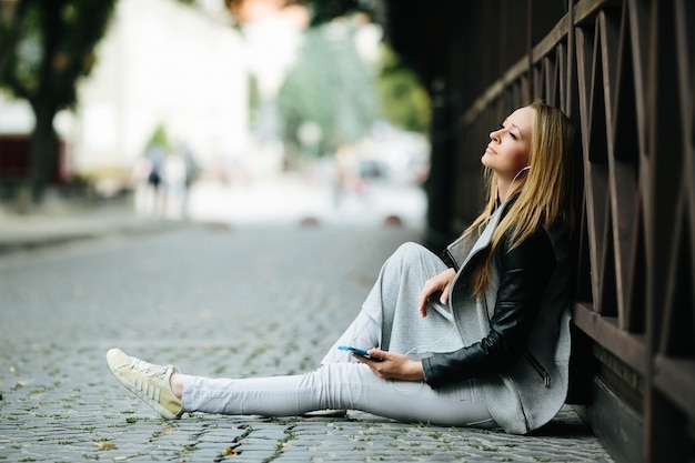 Femme assise et rêve sur le trottoir