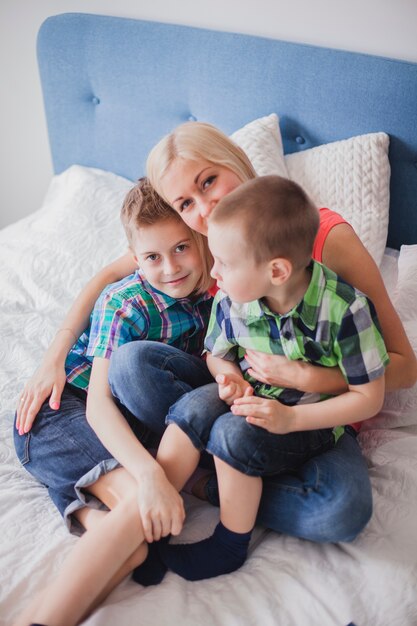 Femme assise avec ses enfants sur le lit