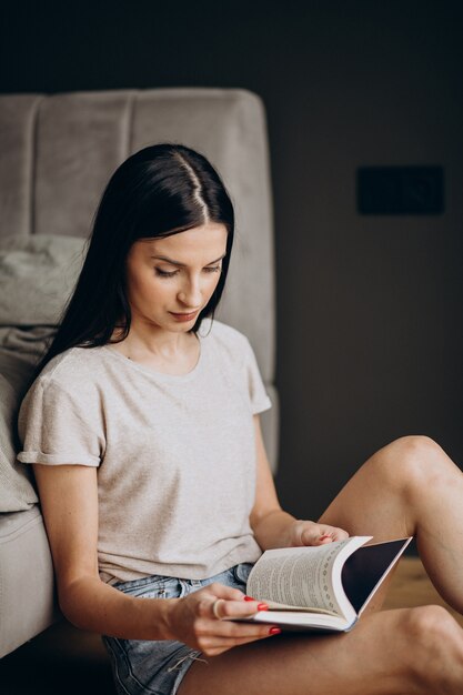 Femme assise sur le sol et livre de lecture