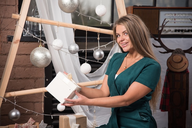 Femme assise sur le sol à la maison avec des cadeaux de Noël