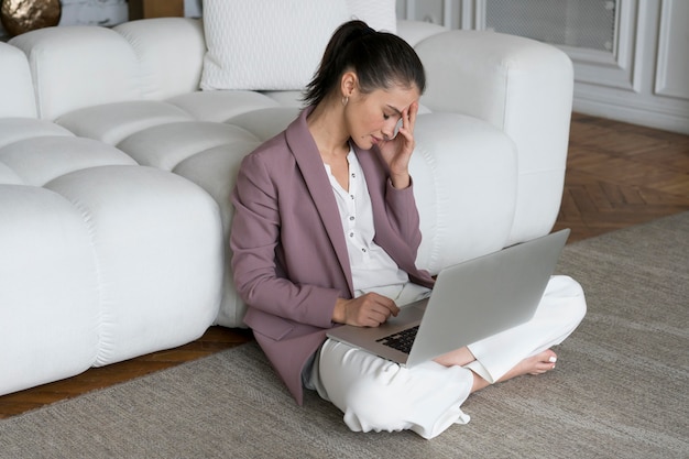 Femme assise sur le sol avec un ordinateur portable sur ses genoux