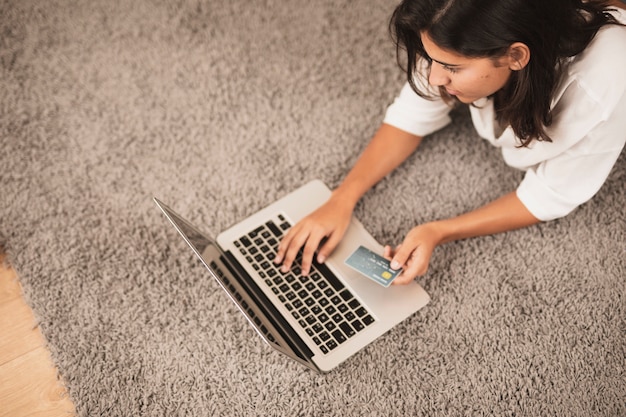 Femme assise sur le sol et travaillant sur un ordinateur portable