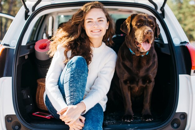 Femme assise avec son chien dans le coffre ouvert