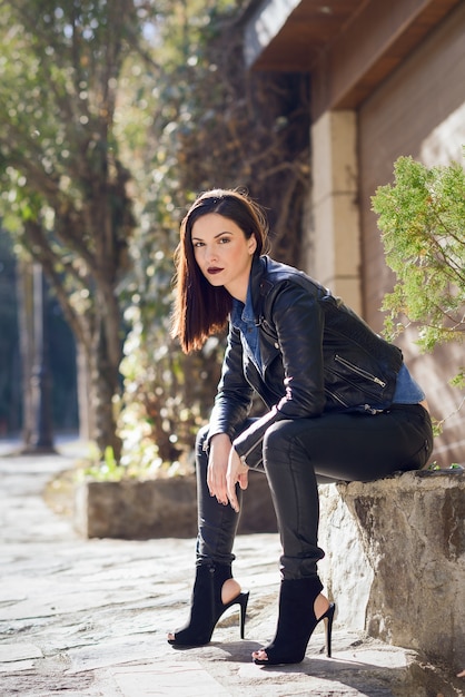 Femme assise avec des talons hauts sur un banc de pierre