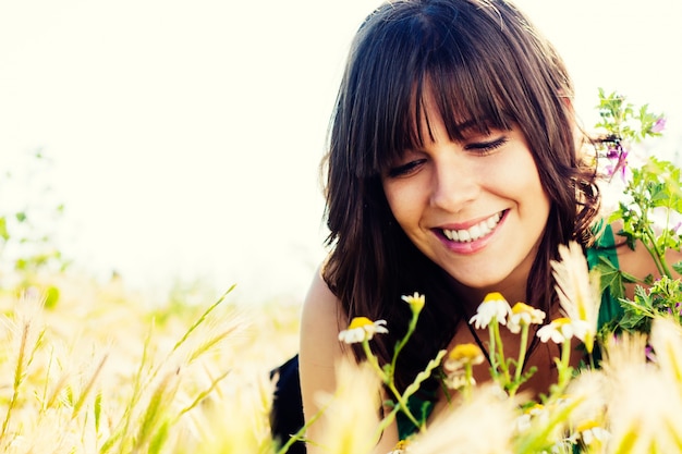 Photo gratuite femme assise sur le terrain et des fleurs reniflage