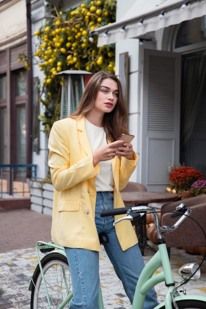Photo gratuite femme assise sur le vélo et tenant le smartphone