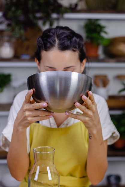 Femme assoiffée de boire du lait d'amande dans un bol en métal dans la cuisine