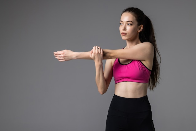 Femme athlétique étirant la main sur le gris