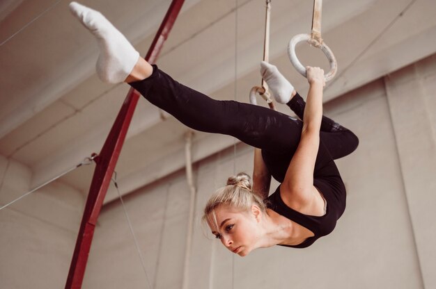 Femme athlétique à faible angle de formation sur les anneaux de gymnastique