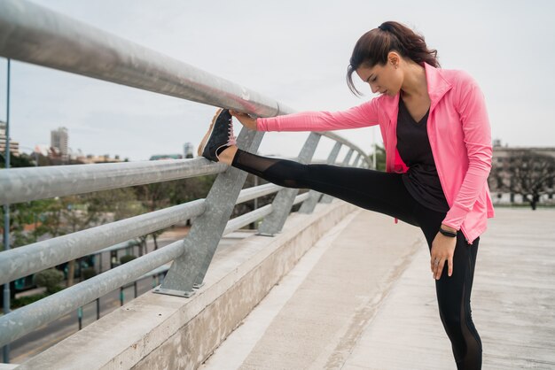 Femme athlétique qui s'étend des jambes avant l'exercice