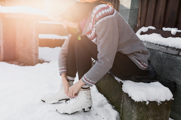 Photo gratuite femme attachant des patins sur un banc