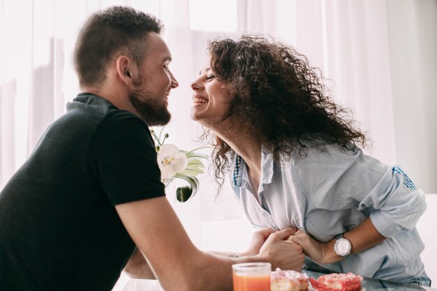 La femme atteint son homme pour un bisou assis à la table à manger