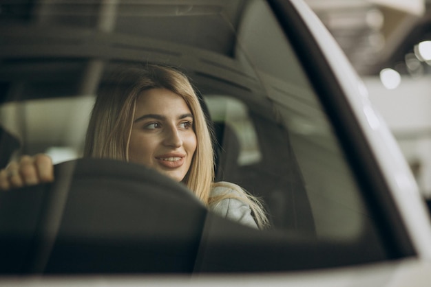 Femme attirante dans la salle d'exposition de voiture achetant une voiture