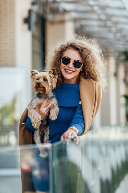 Femme attirante réussie portant au manteau nu tenant le terrier de Yorkshire