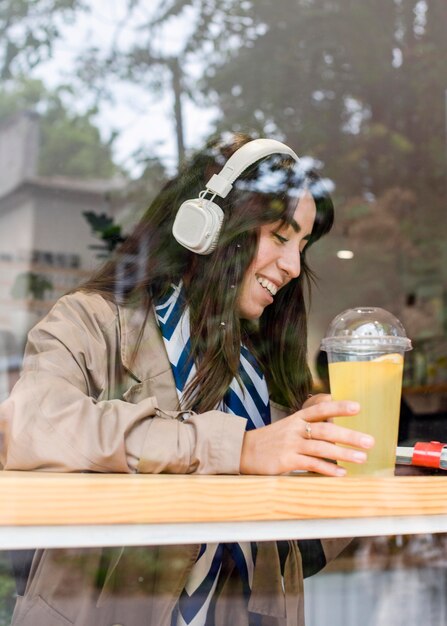 Femme au café avec de la limonade fraîche et des écouteurs