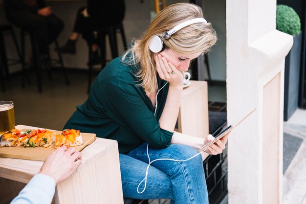 Femme au café ouvert, se concentrant sur une tablette