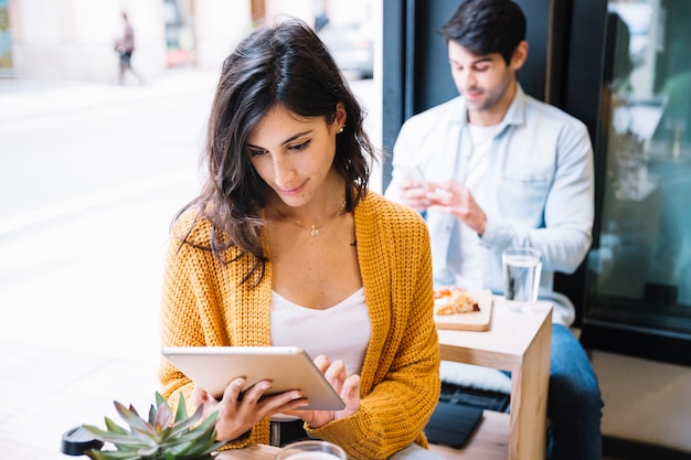 Femme au café travaillant sur une tablette