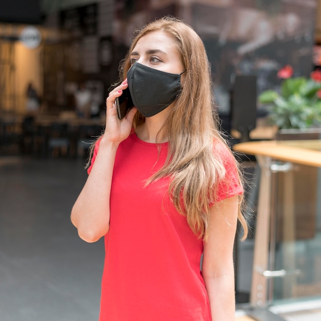 Femme au centre commercial avec masque parlant sur mobile