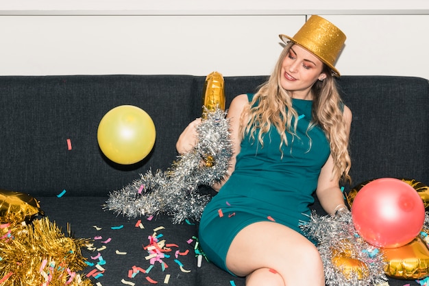 Femme au chapeau assise sur un canapé avec des guirlandes