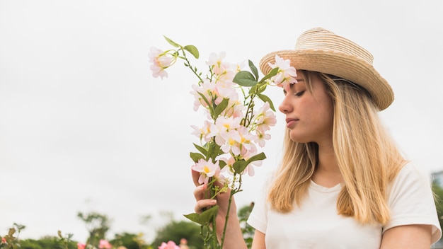 Femme au chapeau sentant les fleurs légères