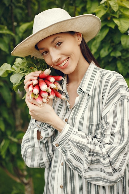 Photo gratuite femme au chapeau tenant des radis frais