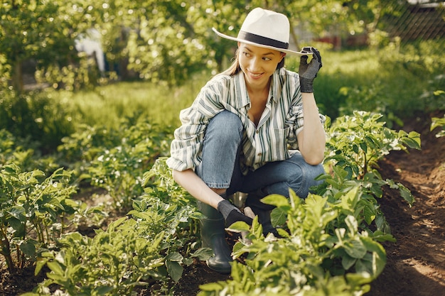 Femme au chapeau travaillant dans un jardin