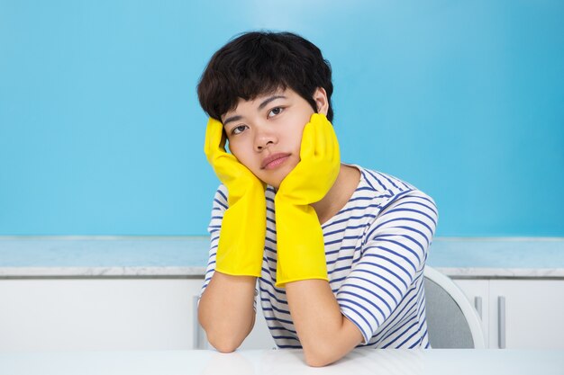 Femme au foyer fatiguée dans des gants de protection dans la cuisine